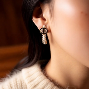 Close-up of model wearing 18k gold plated CD logo earrings with white pearls and crystals
