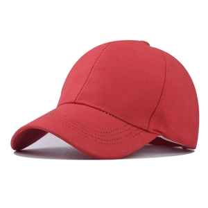 Detail of red cotton baseball cap showing curved brim and reinforced stitching