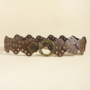 Dettaglio cintura in pelle marrone con rivetti dorati e fibbia in bronzo antico intagliata