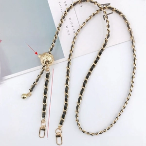 Detail of adjustable gold metal chain with black leather weaving and sliding ball
