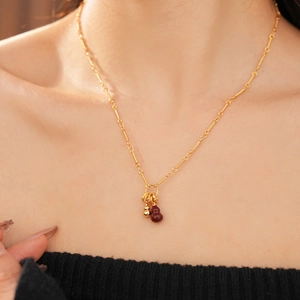 Detail shot of 18k gold plated necklace with red agate gourd pendant on a model's neck