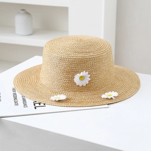 Detail of hand-woven straw hat featuring three 3D white daisies and intricate texture