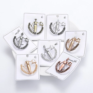 Detail view of Lady Justice Libra brooches in gold, silver, and bronze on display cards