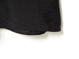 Détail de la couture de l'ourlet et du tissu froissé sur une robe noire plissée