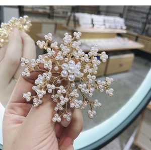 Detail of elegant gold snowflake brooch with white pearls held in hand for winter coats