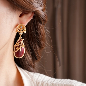 Close-up of vintage flower earrings with water drop ruby pendants worn by a model
