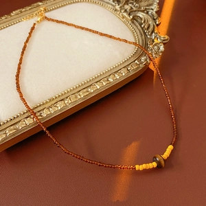 Close-up of vintage amber beaded necklace with brown tiger eye stone on leather background