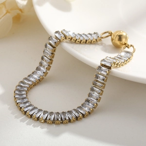 Golden tennis bracelet with rectangular cubic zirconia and magnetic clasp on white porcelain