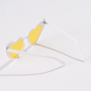 Detail of white heart-shaped sunglasses featuring stylish transparent yellow lenses