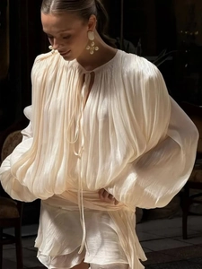 Detail of ivory pleated chiffon dress featuring lantern sleeves and delicate tie neck design