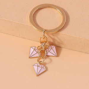Detailed view of pink diamond-shaped pendants with golden ring on a beige display base