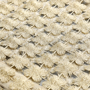 Macro detail of champagne gold lace with floral 3D embroidery and metallic thread