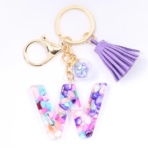 Detail of purple tassel and colorful resin letter W keychain with gold ring and charm