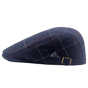 Detail of blue herringbone flat cap featuring a bronze adjustable metal side buckle
