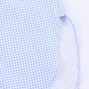 Close-up of side slit and hem details on this blue and white plaid shirt for women
