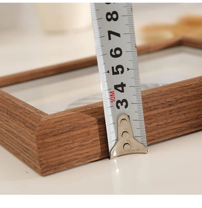 Close-up of a deep walnut wood specimen frame showing 3cm depth measured with a tape measure