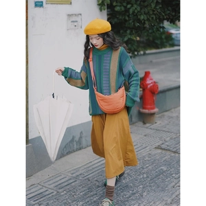 Outdoor street view of a woman wearing a mustard yellow skirt and orange nylon crossbody bag