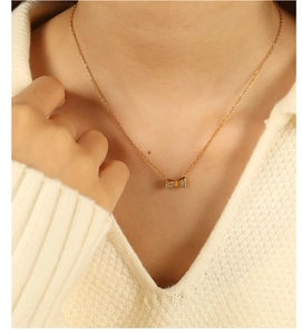 Gros plan du collier pendentif nœud doré serti de micro-pierres de zircon brillant