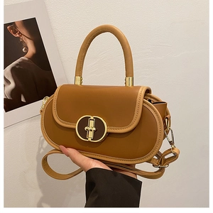 Dettaglio borsa vintage in pelle marrone con chiusura dorata e manico strutturato