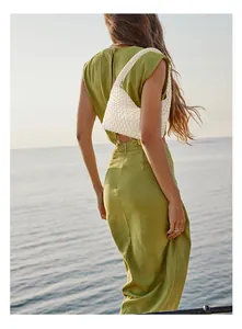 Detail of white woven leather hobo bag styled with a backless green dress on the beach