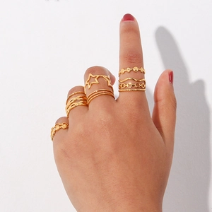 Detail of stacked gold woven rings featuring star and chain patterns on model's hand