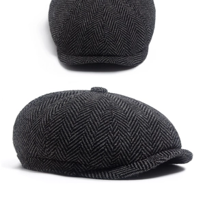 Close-up of a classic dark grey newsboy cap with textured herringbone wool fabric