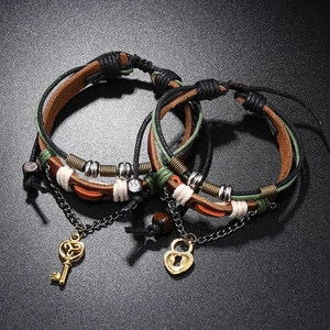 Gros plan détaillé de bracelets de couple en cuir tressé rétro avec pendentifs clés.