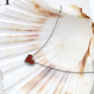 Macro shot of 18k gold plated heart pendant with red inlay inside a decorative shell
