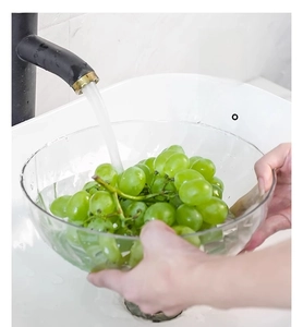 Close-up of clear fruit drain bowl washing green grapes under a modern black faucet