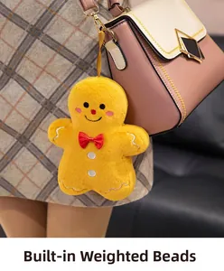 Plush gingerbread man keychain with red bow on a pink bag showing weighted pellets detail