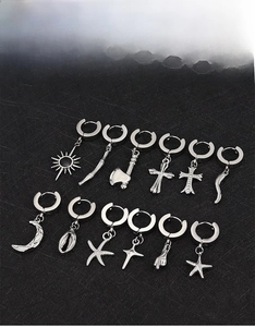 Flat lay of silver titanium steel hoop earrings featuring cross moon and star charms