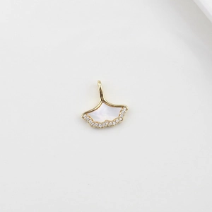Macro detail of 18k gold ginkgo leaf pendant with mother-of-pearl and pavé zircon stones
