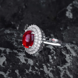 Macro shot of oval ruby red stone ring with zircon halo on volcanic rock background