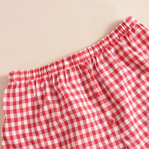 Detail of red and white plaid fabric featuring elastic waistband and three red buttons