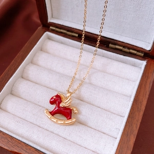 Detailansicht der Goldkette mit rotem Emaille-Flügelpferd-Anhänger in einer Schmuckschatulle
