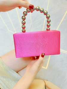 Detail of fuchsia satin evening bag with a metallic silver beaded top handle and sleek finish