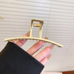 Detail view of large matte gold metal hair claw clip with strong spring and sleek arc design