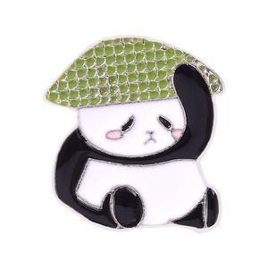 Close-up of a cute sitting panda enamel pin wearing a green textured hat on white background