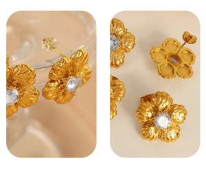 Detail of vintage gold flower studs with five-petal texture and central crystal stones