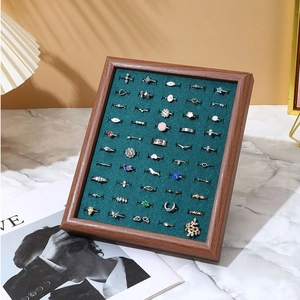 Macro view of walnut wood ring tray with green velvet slots and various jewelry
