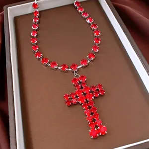 Luxury silver-tone necklace with sparkling red rhinestone cross pendant on silk background