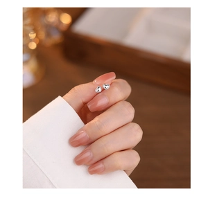 Close-up of minimalist silver heart-shaped stud earrings held between fingertips