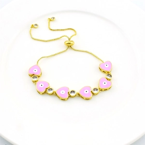 Detail of gold evil eye bracelet with pink heart charms and adjustable slide clasp