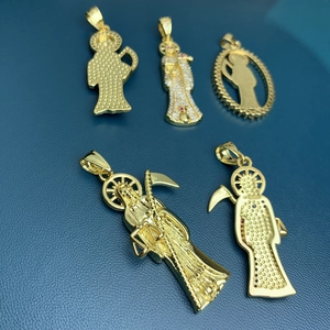 Gold plated Santa Muerte pendants with zircons on blue leather background texture