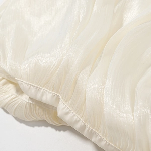 Elegant sleeveless pleated top in apricot with smooth satin finish and round neckline