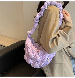 Detail of lavender quilted cloud bag with pleated strap worn by a model in soft lighting