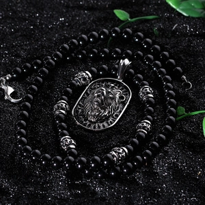 Punk titanium steel lion head pendant necklace with black beads on a dark sand background