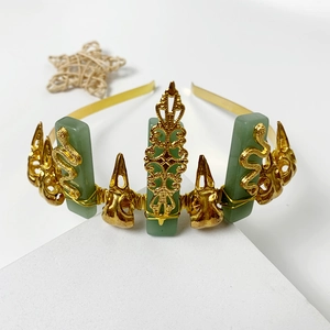 Close-up of golden crown headband with green aventurine stones and carved snake details