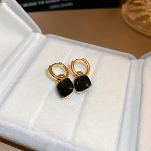 Detailed close-up of gold-plated black enamel earrings in a blue velvet display box