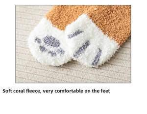 Close-up of fluffy orange coral fleece socks with cute grey cat paw pattern design